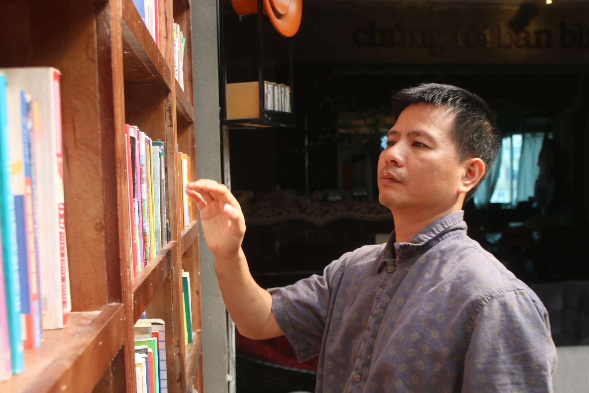 Anh Phí Lân Khoa - chủ chuỗi cà phê Tiny Cafe đang sắp xếp lại giá sách. Ảnh: Đức Huy.